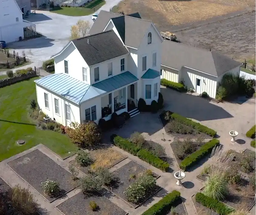 Aerial view of a charming two-story white house with a blue metal roof
